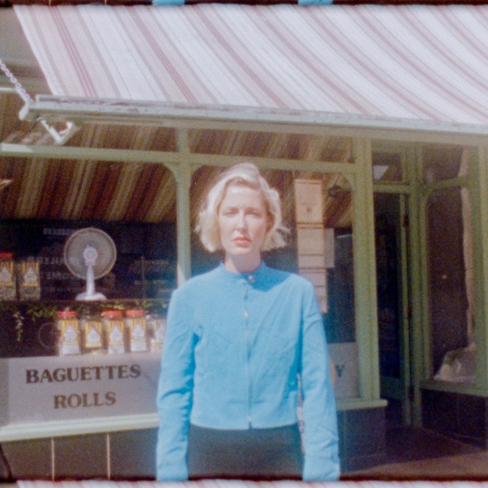 Photo of Charlotte James standing in front of a shop window with a striped awning