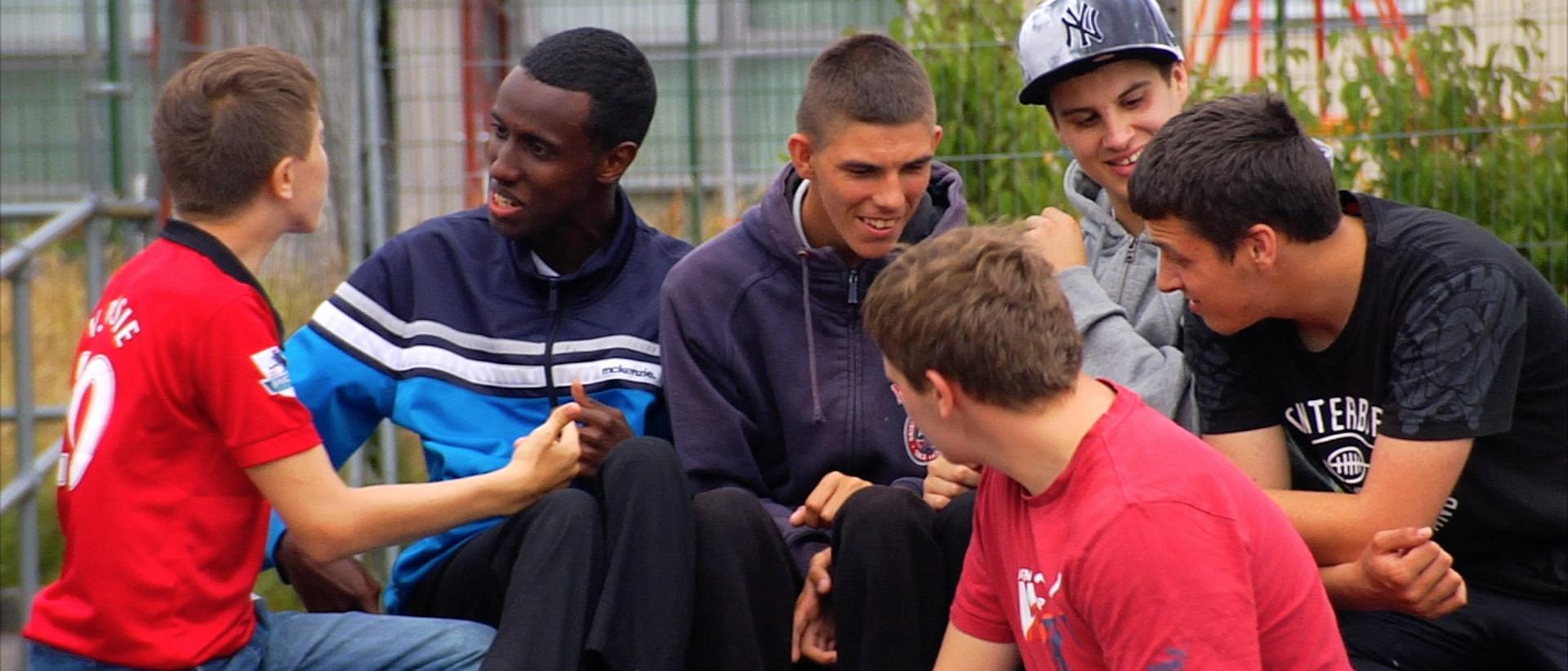 a group of young people sitting outside talking and laughing