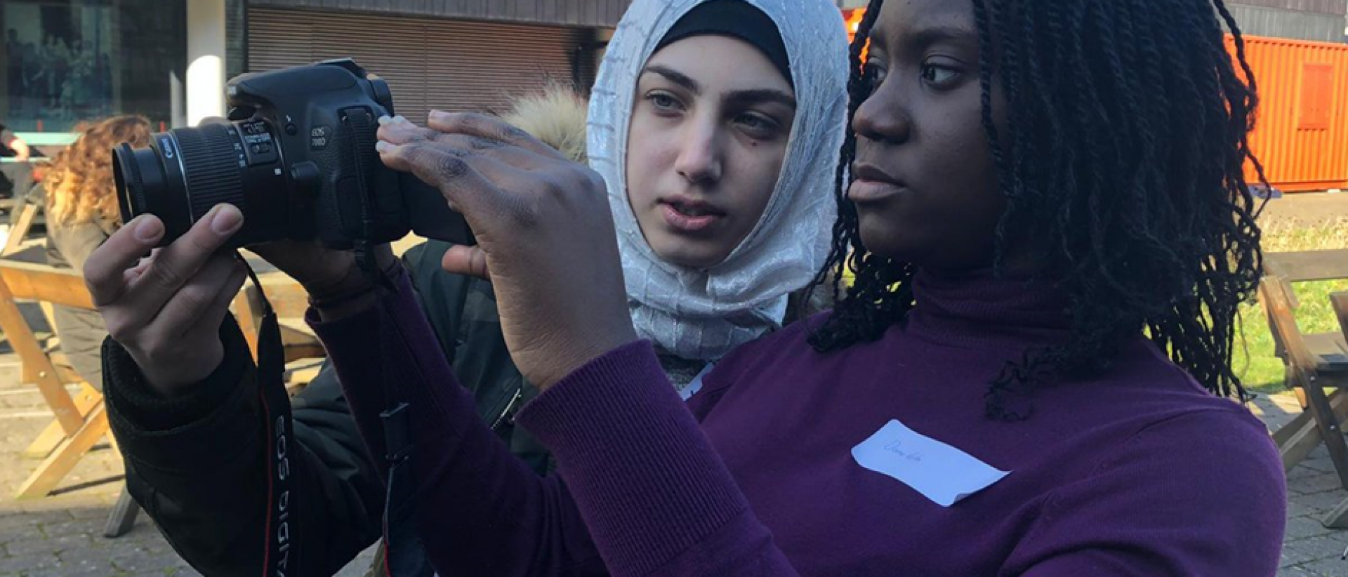 a person showing another person how to shoot a film on a digital camera