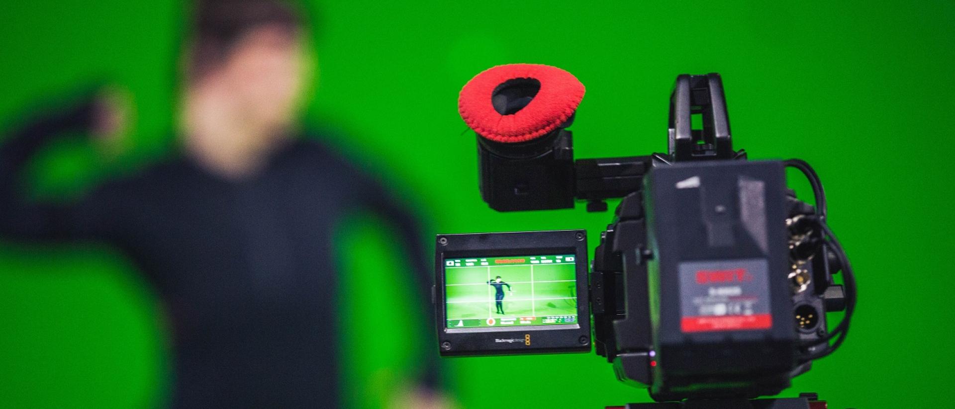 a camera recording a person performing in front of a greenscreen