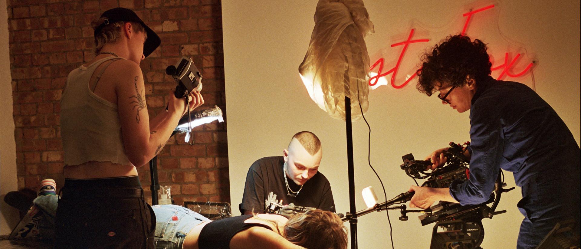 behind the scene photo of being seen, with a camera crew filming a person getting a tattoo