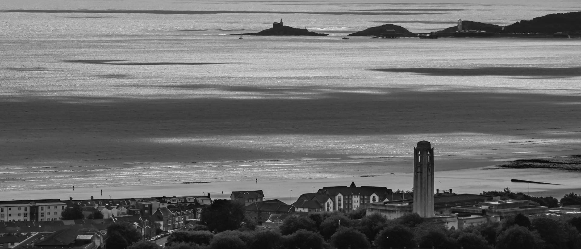 a black and white photo of Swansea featuring the city and sea