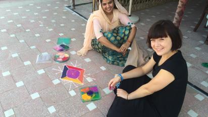 two people sitting on the floor creating rangoli art