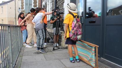 a group of young people outside a building making a film