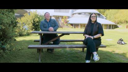 A photo of Gaz Bailey and Bia Edwards-Behi sitting on a picnic bench outside the Aberystwyth Arts Centre.