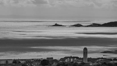 a black and white photo of Swansea featuring the city and sea